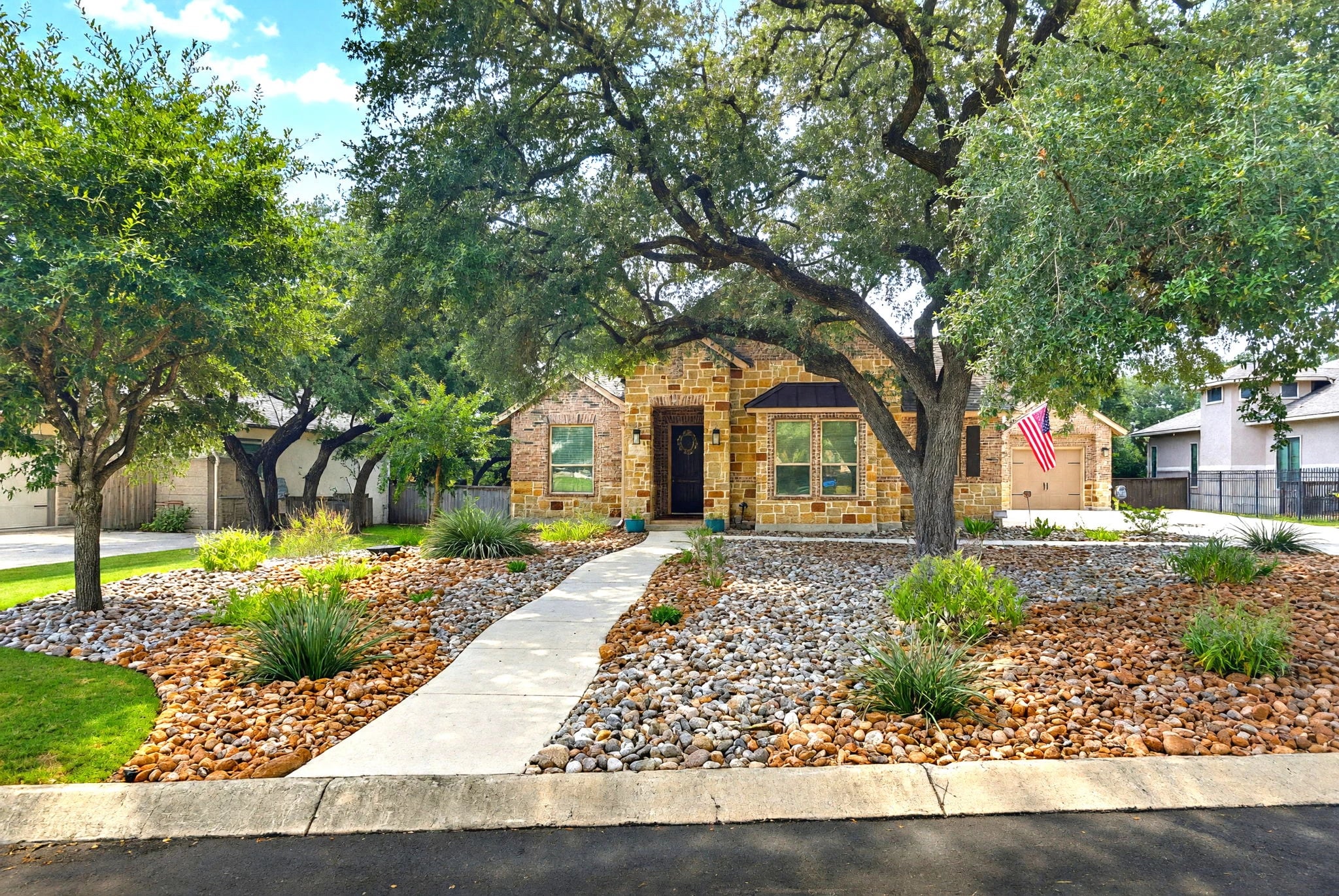 A stone Texas Hill Country home behind a live oak